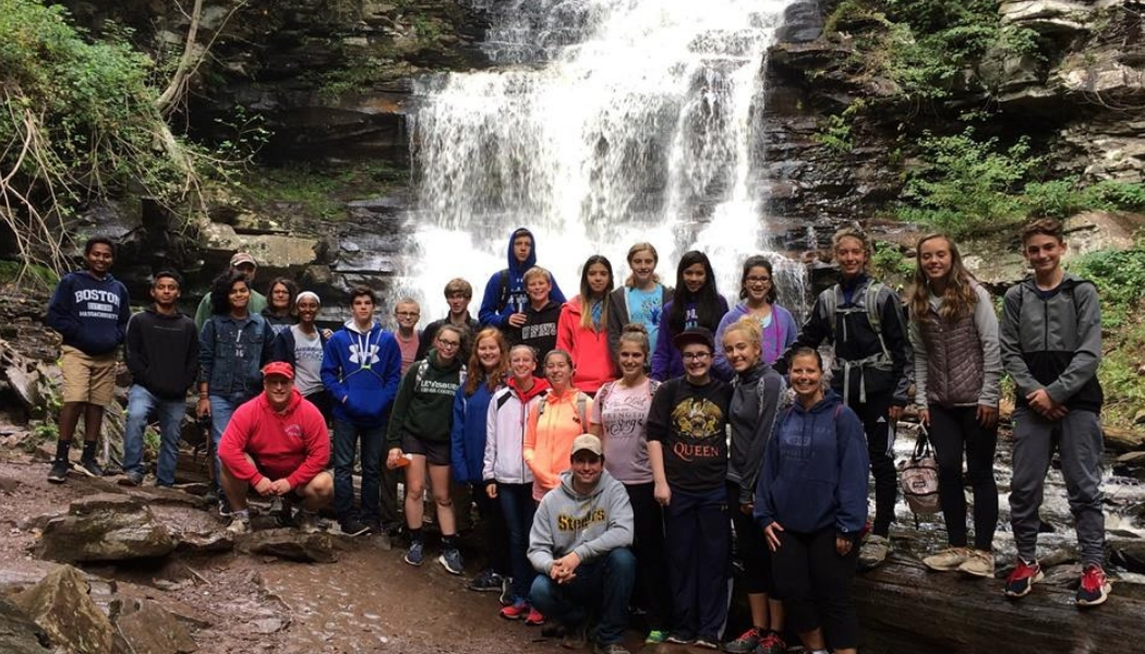 A group of students posing at the base of a waterfall
