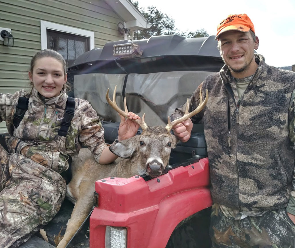 A girl and man with a dead buck