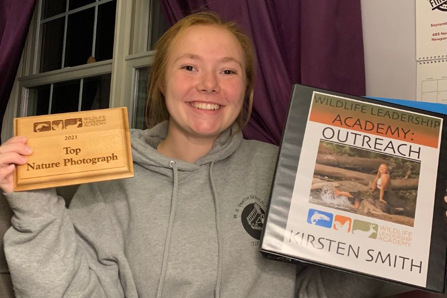 Kirsten posing with her outreach record book and award.